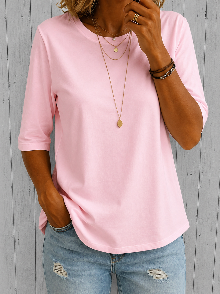 Soft pink round-neck top with half sleeves and a relaxed fit, styled with light-wash distressed jeans.