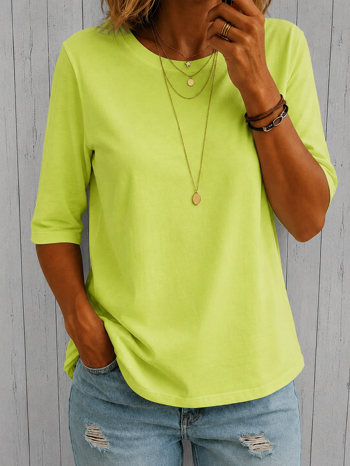 Neon lime green round-neck top with half sleeves and a relaxed fit, styled with distressed blue jeans.