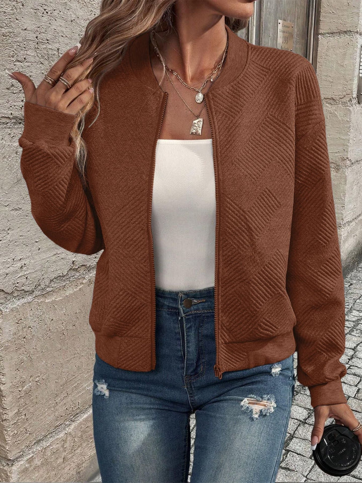 Brown textured zip-up cardigan with a ribbed stand collar, cuffs, and hem worn over a white top and distressed jeans.