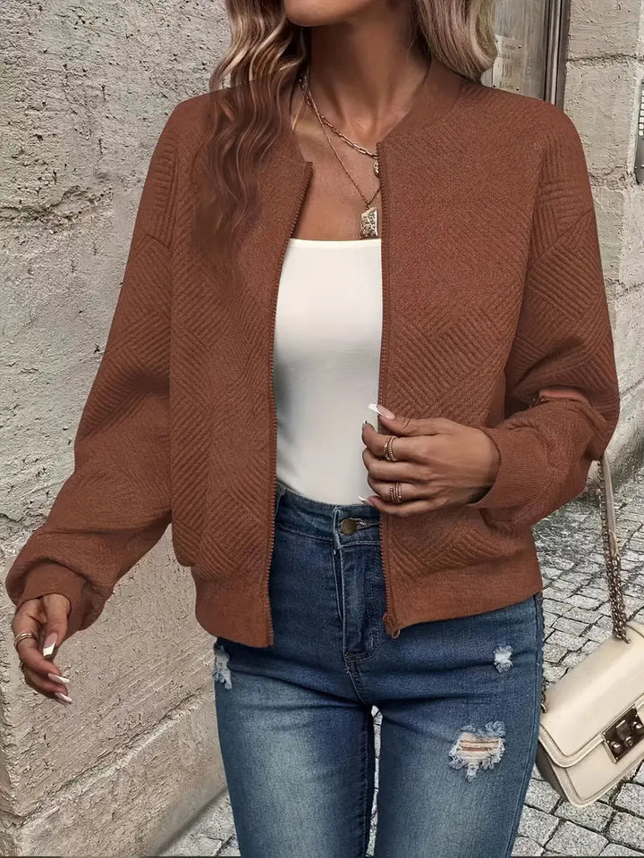 Brown textured zip-up cardigan with a ribbed stand collar, cuffs, and hem worn over a white top and distressed blue jeans.