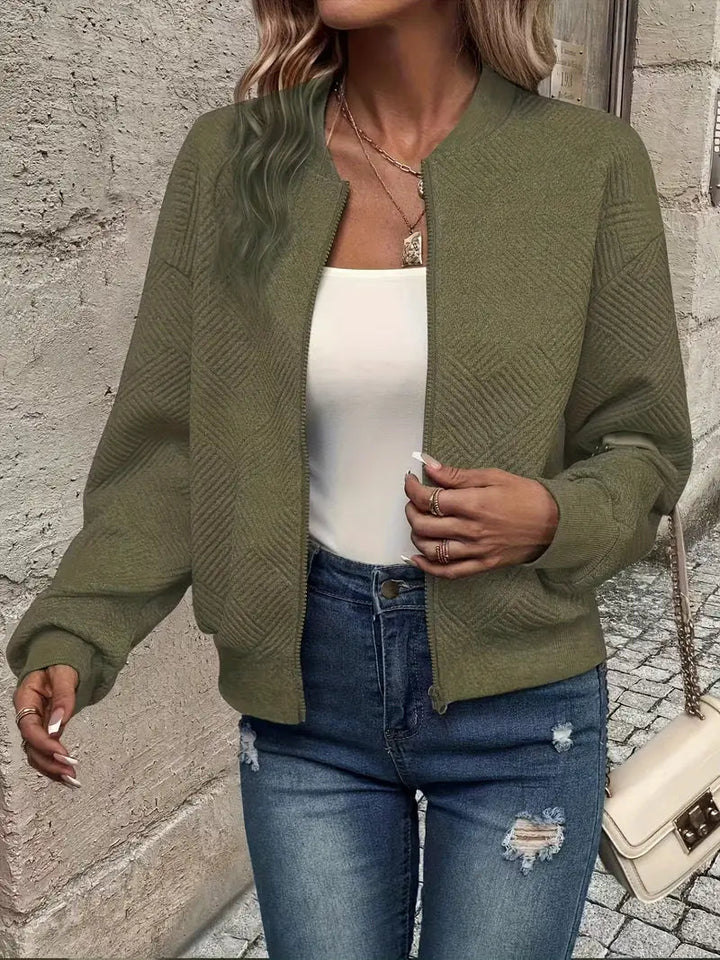 Olive green textured zip-up cardigan with a ribbed stand collar, cuffs, and hem worn over a white top and blue jeans.