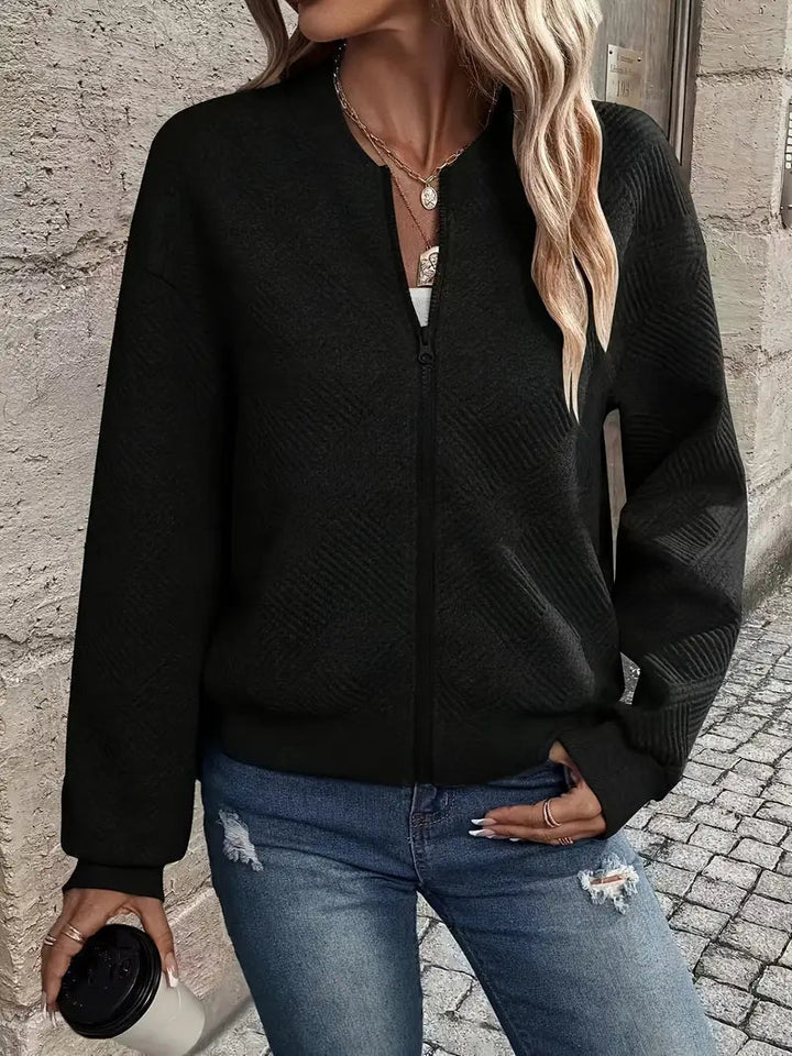Black textured zip-up cardigan with a ribbed stand collar, cuffs, and hem, styled with distressed blue jeans.