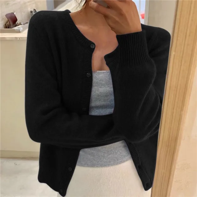 Black knit crew neck cardigan with a button-front closure and ribbed cuffs, worn over a grey tank top.