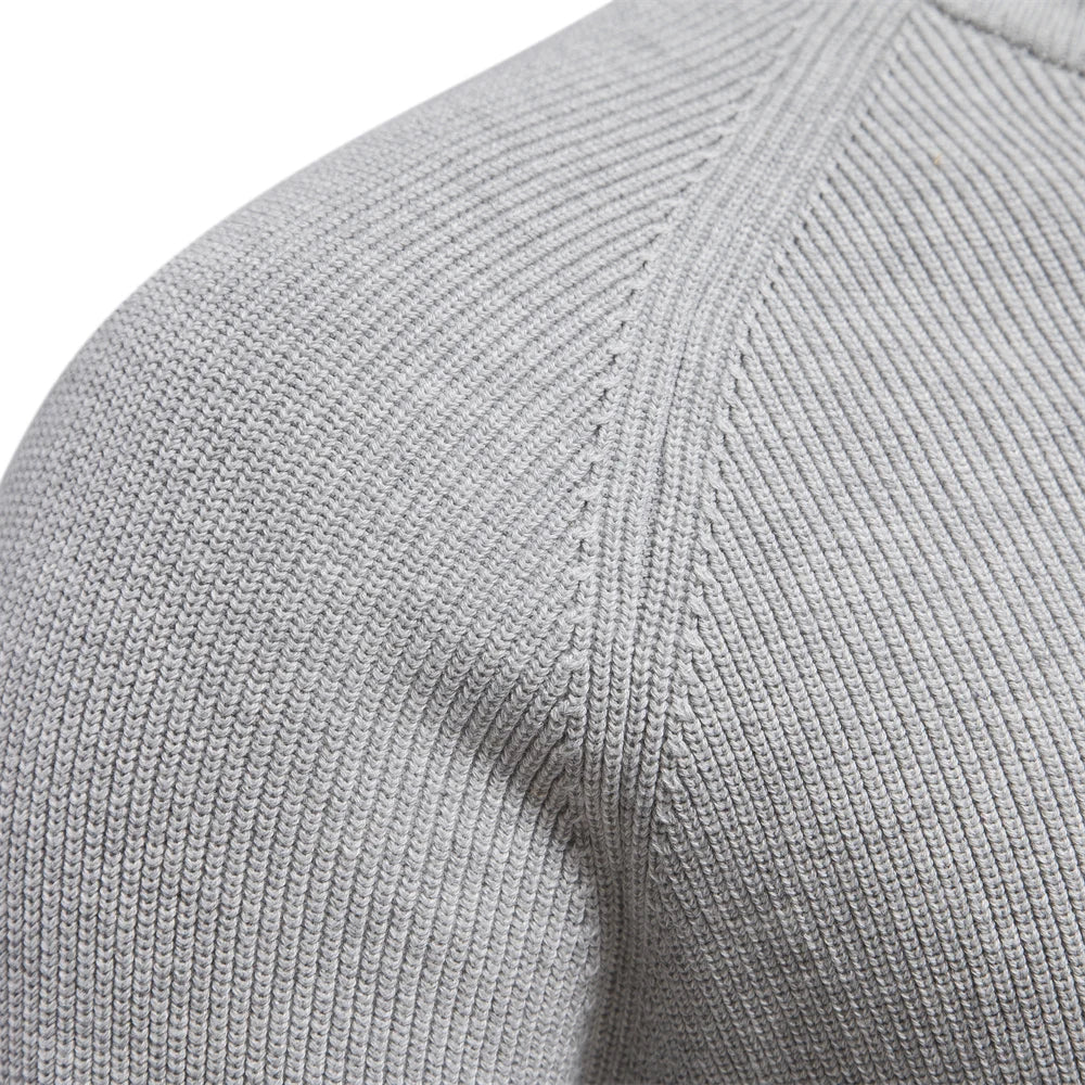 Close-up of a light grey men's quarter-zip knit sweater showing the soft, textured fabric and raglan sleeve detail.