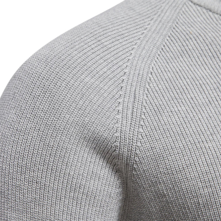 Close-up of a light grey men's quarter-zip knit sweater showing the soft, textured fabric and raglan sleeve detail.