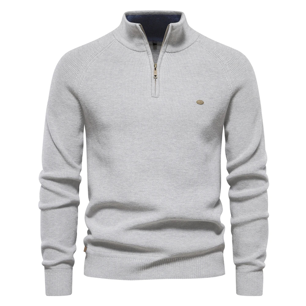 Light grey men's quarter-zip knit sweater with ribbed sleeves, a high collar, and a small metallic logo detail.