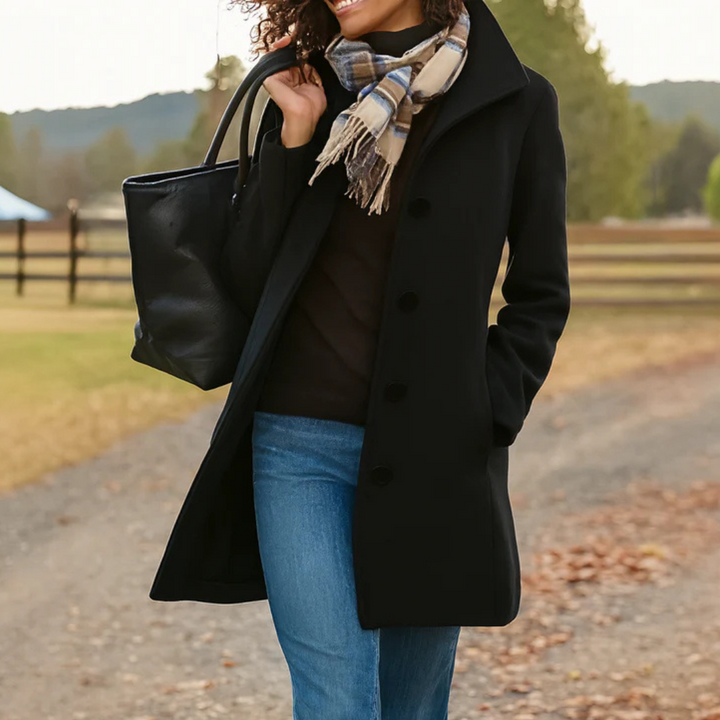 Black mid-length button-up winter coat with a structured collar, worn with a plaid scarf and a black leather tote bag.