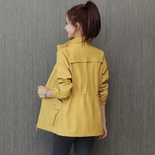 Yellow lightweight jacket with a stand-up collar, drawstring waist, and front pockets worn by a woman.