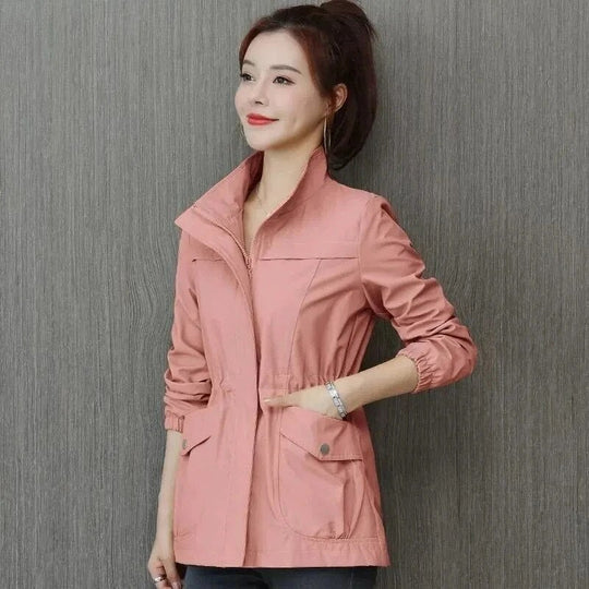 Woman wearing a dusty pink lightweight jacket with a stand-up collar, full zip front, and drawstring waist.