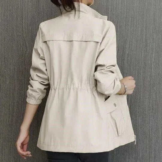 Beige lightweight jacket with a stand-up collar, drawstring waist, and front pockets, shown from the back.