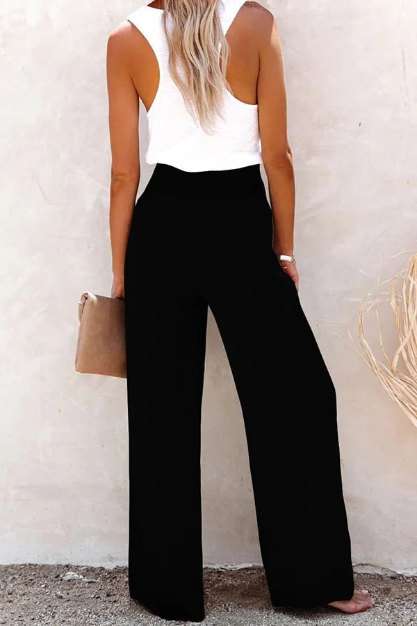 Woman wearing black high-waisted wide-leg linen trousers with a relaxed fit and smocked waistband.