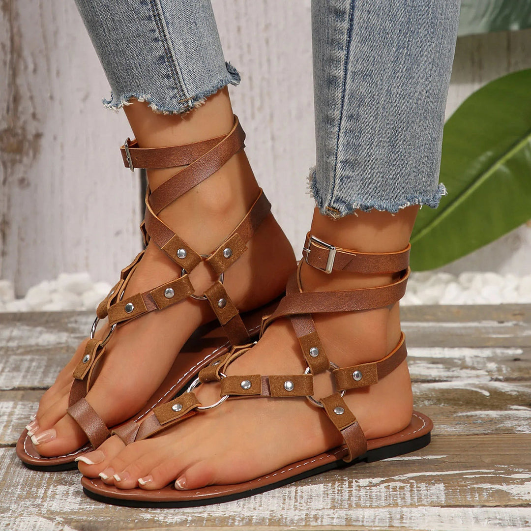 Brown leather Ellie gladiator flat sandals with wrap-around ankle straps and metal studs.