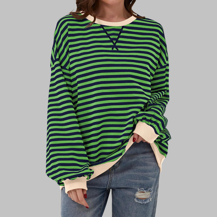 Oversized green and navy striped sweatshirt with cream ribbed trim and a round neckline worn with distressed jeans.