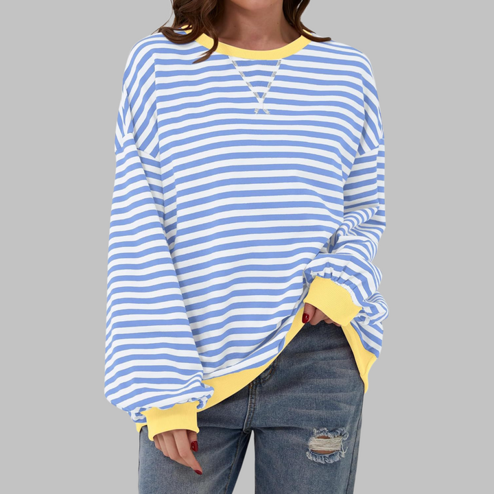 Oversized blue and white striped sweatshirt with a yellow ribbed crew neckline and cuffs, worn with distressed jeans.