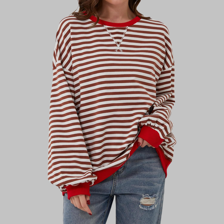 Oversized brown and white striped sweatshirt with contrast red ribbed neckline and cuffs, worn with distressed blue jeans.