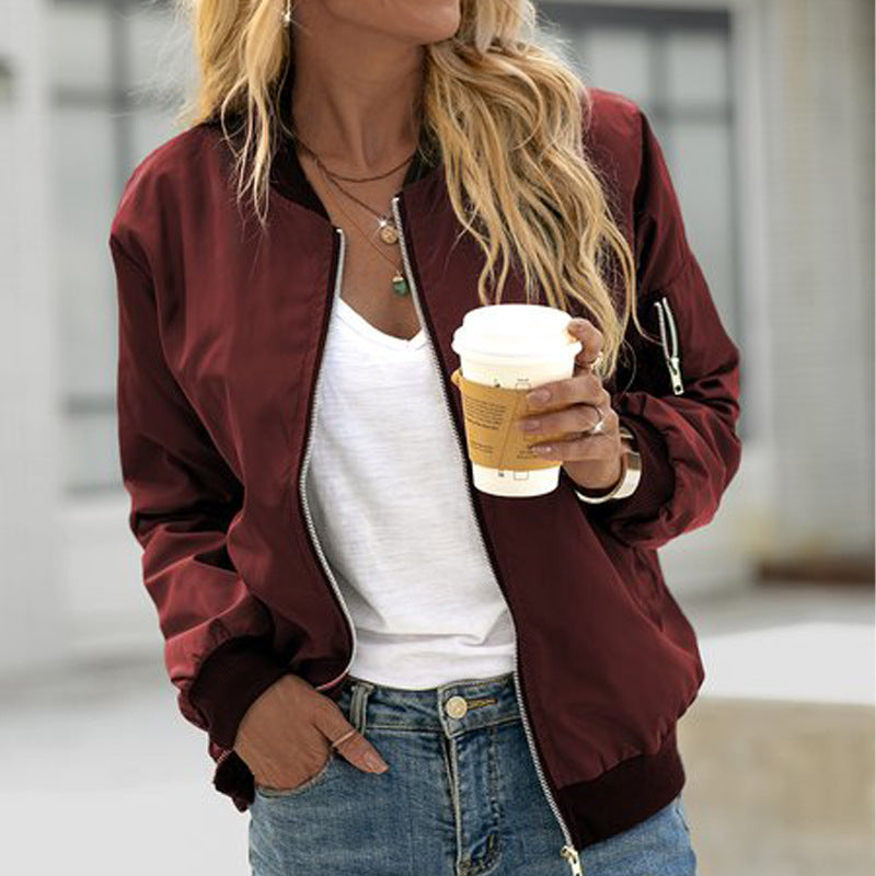Woman wearing a burgundy zip-up bomber jacket with a utility sleeve pocket, elasticated cuffs, and a white t-shirt.