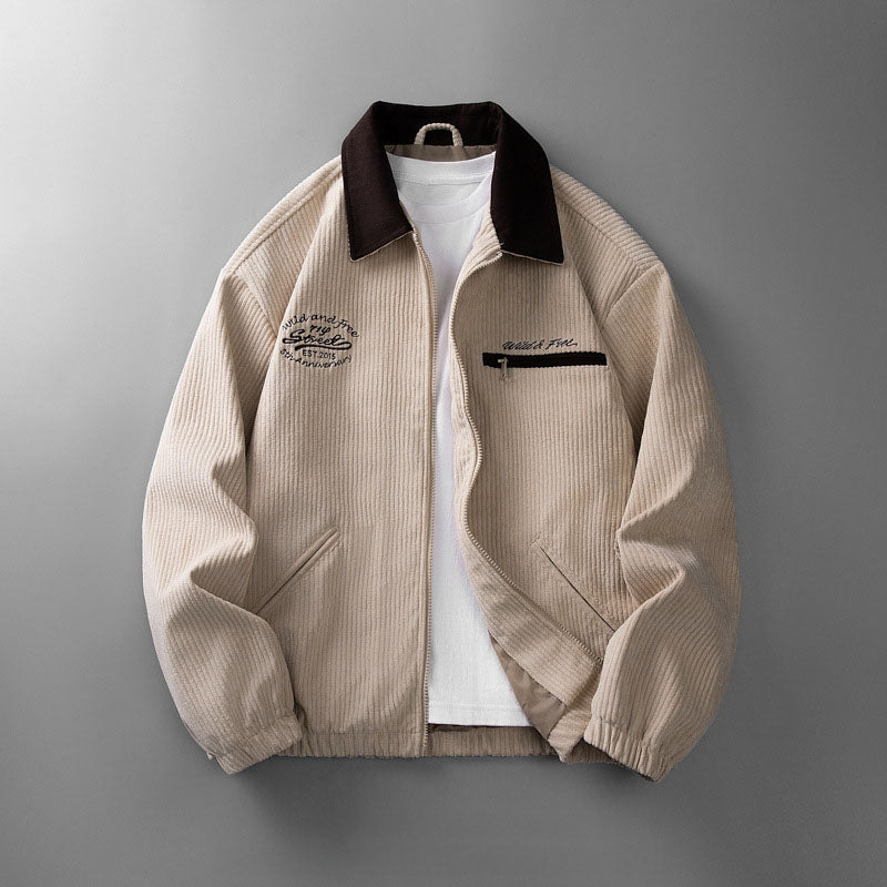 Beige corduroy zip-up jacket with a dark brown collar, chest embroidery, and side pockets over a white t-shirt.