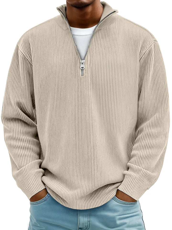 Beige men's ribbed half-zip sweater with a stand collar and relaxed fit, worn over a white shirt and blue jeans.