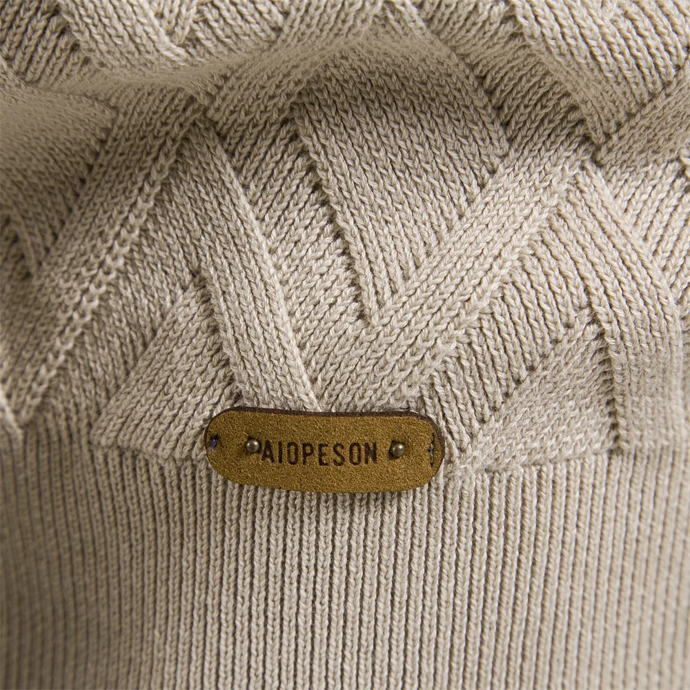 Beige men's crew neck jumper featuring a textured diamond knit pattern and a branded leather hem patch.