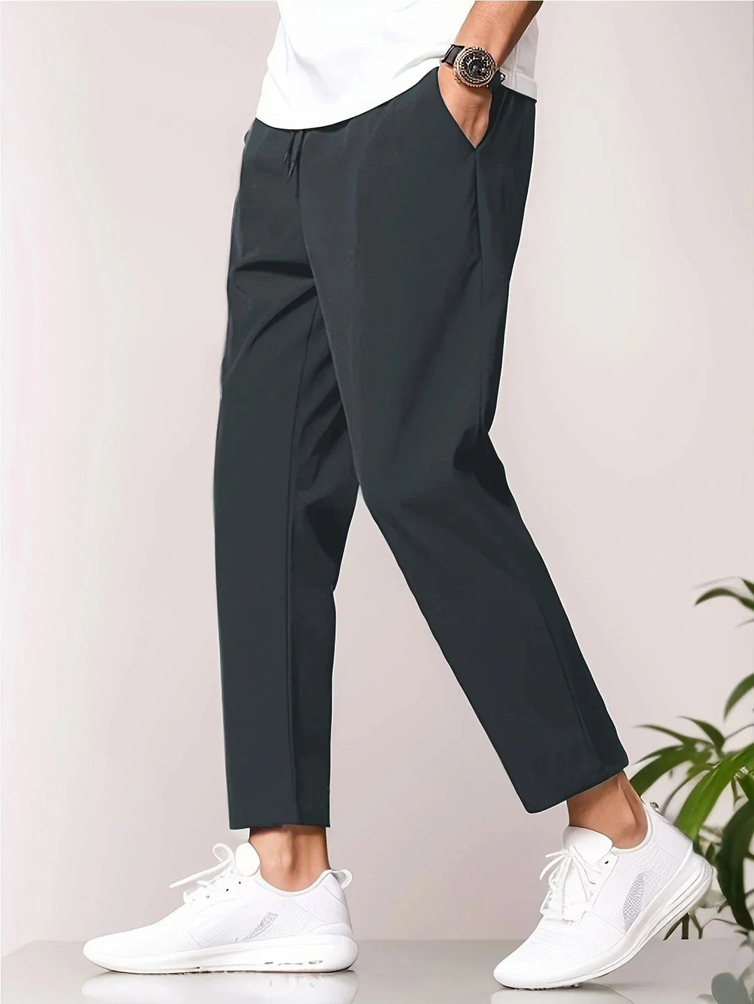 Men wearing charcoal grey tapered trousers with a drawstring waist, side pockets, and a modern cropped ankle length.