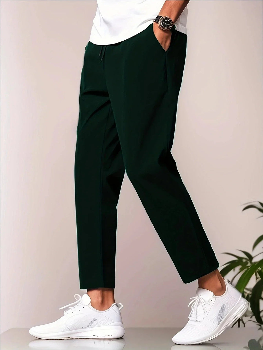 Dark green men's tapered trousers with a drawstring waist, side pockets, and a modern cropped ankle length.