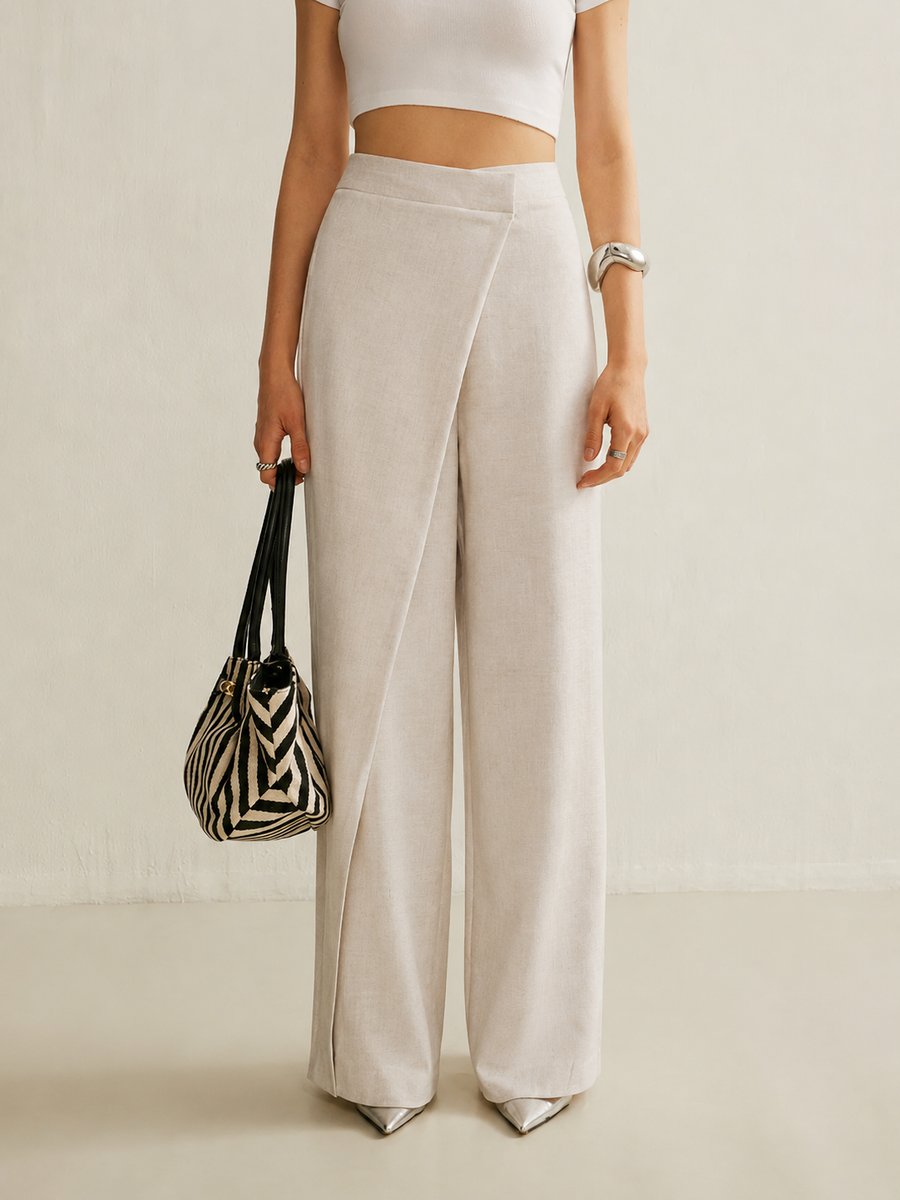 Beige high-waisted wide-leg trousers with a modern asymmetric wrap front panel and a smooth, tailored finish.