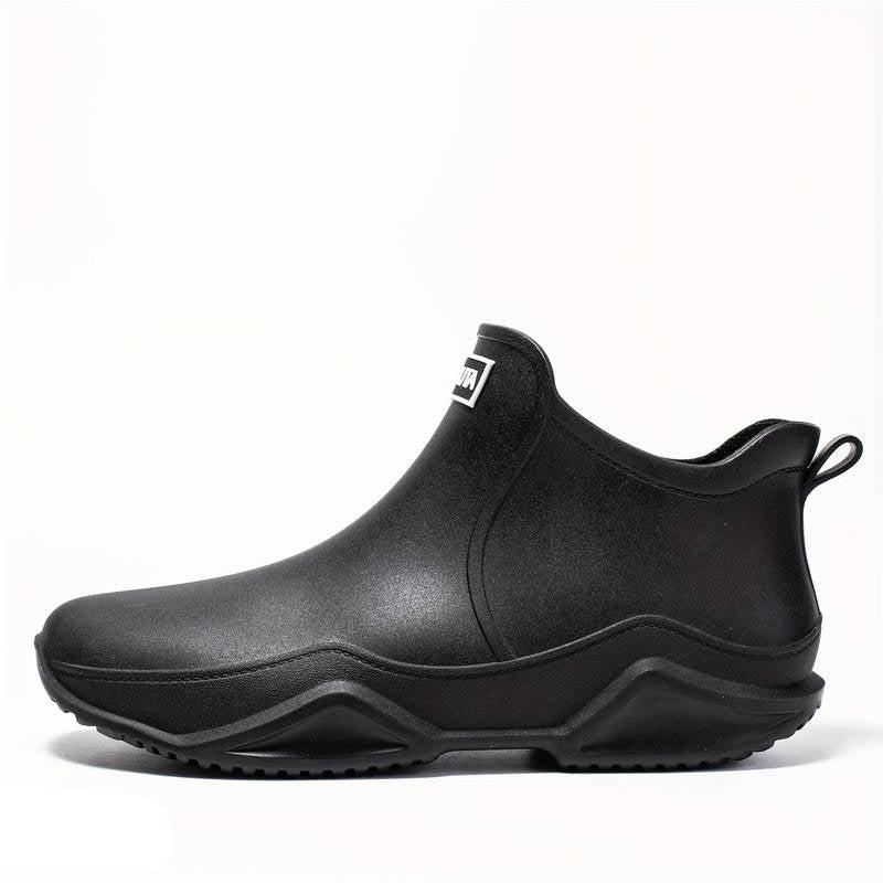 Black waterproof Elodie ankle rain boots with a sleek slip-on design and chunky, grippy wave-tread outsole.