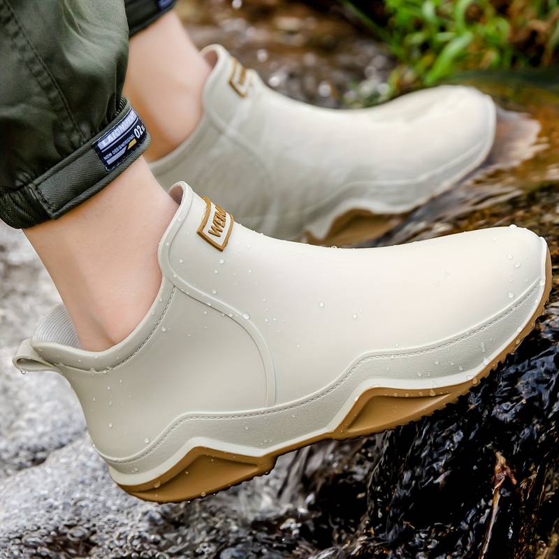 Cream-colored waterproof slip-on ankle rain boots with a chunky, grippy wave-tread sole for wet weather comfort.
