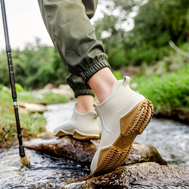 Beige waterproof slip-on ankle rain boots featuring a chunky brown wave-tread outsole for superior grip on wet terrain.