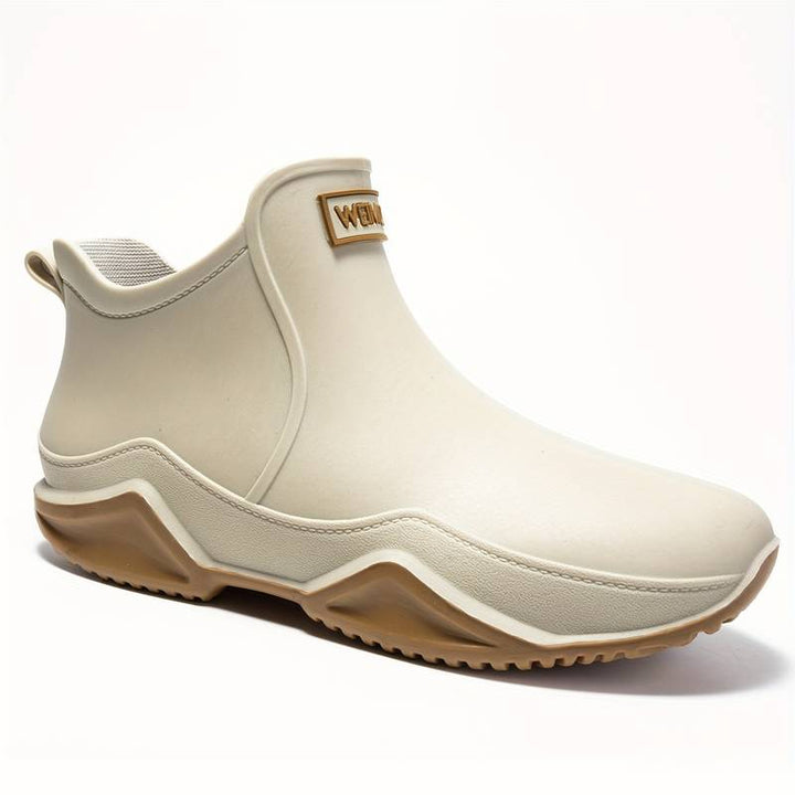Beige waterproof Elodie ankle rain boots with a slip-on design and chunky, grippy wave-tread sole for wet weather.