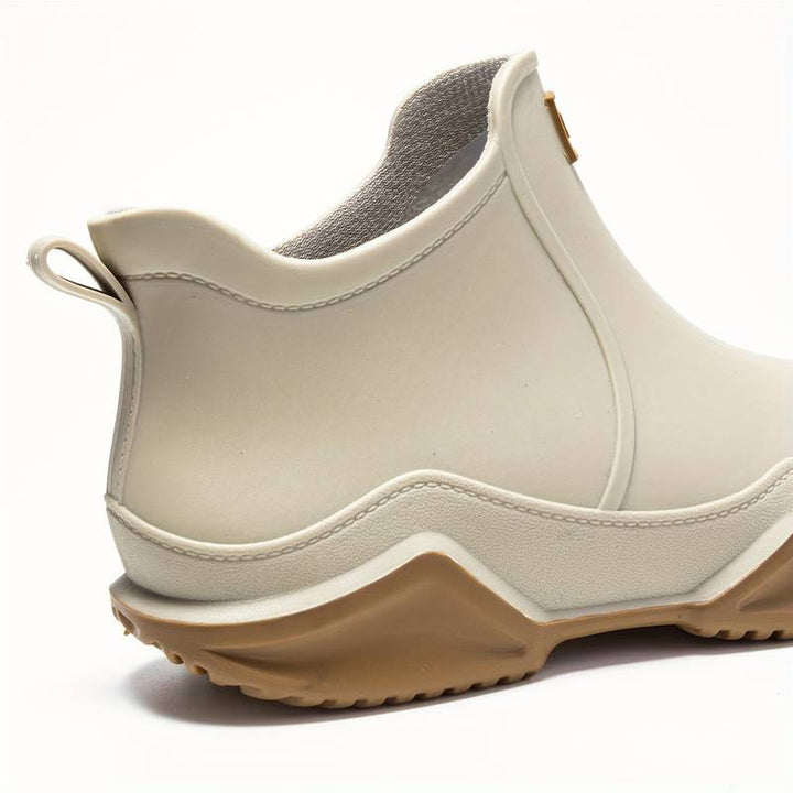 Cream-colored waterproof ankle rain boots with a convenient pull tab and a chunky, grippy wave-tread gum sole.