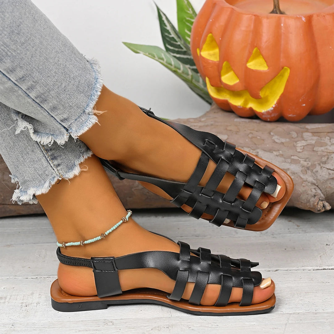 Black woven leather fisherman flat sandals with a slingback strap on a model.