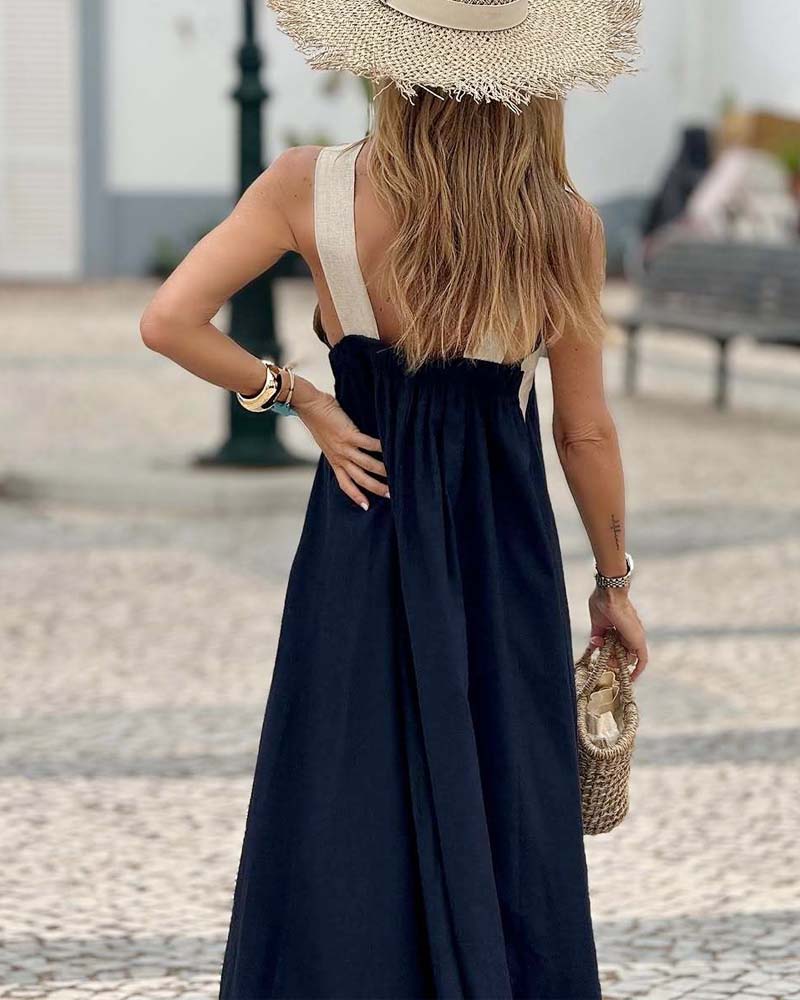 Women's Elsie navy crossover maxi dress with wide straps, flowing skirt, and straw hat.