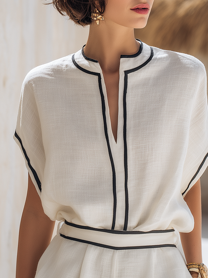Off-white linen-look top with a split neckline and black contrast trim, paired with matching shorts.