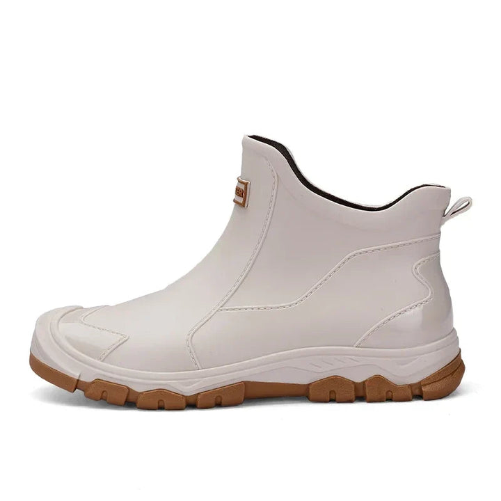 Off-white waterproof ankle rain boots with a smooth finish, rear pull tab, and a rugged brown lug sole for grip.