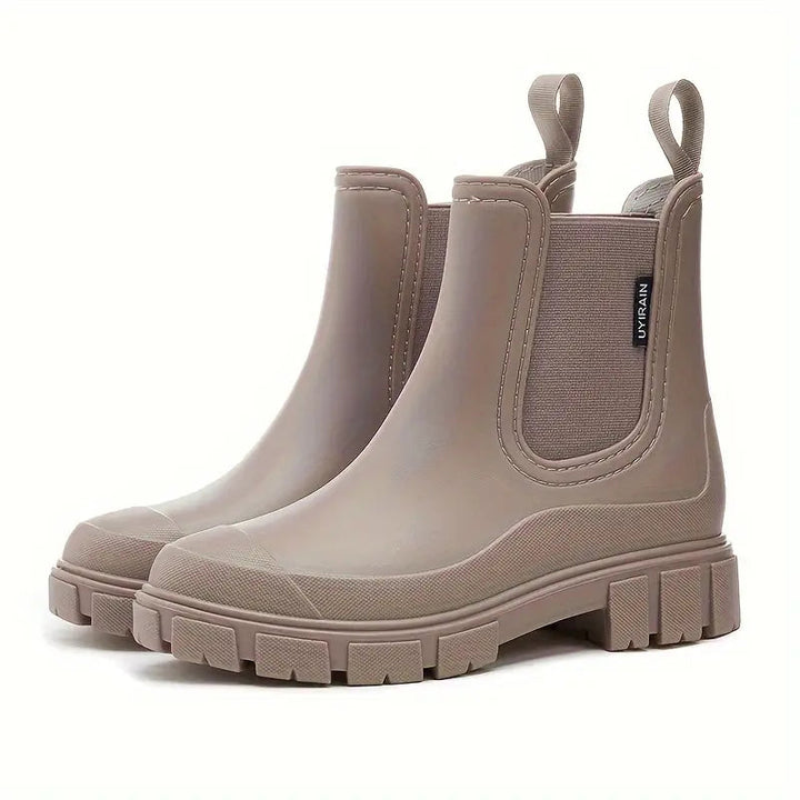 Taupe waterproof Chelsea rain boots with a chunky lug sole, side gussets, and pull tabs on a white background.