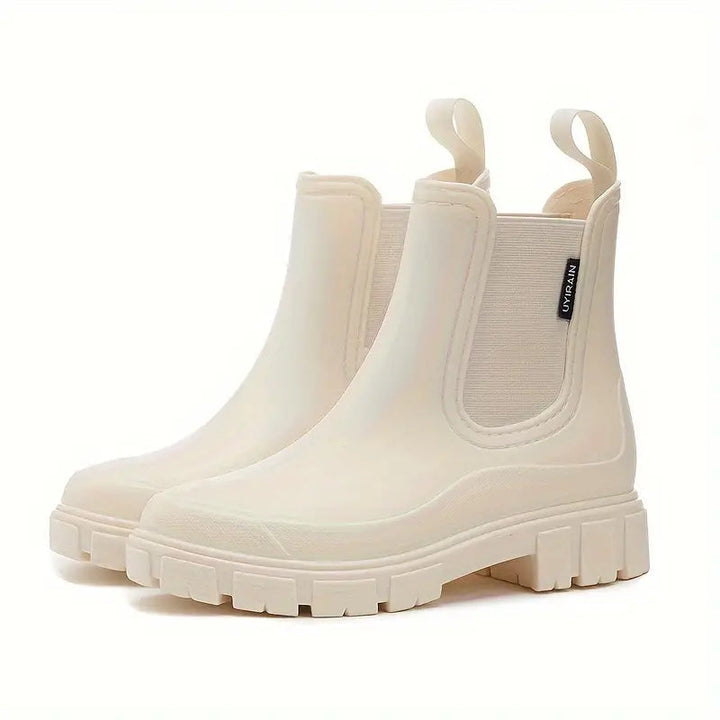 Off-white waterproof Chelsea rain boots with a chunky lugged sole, side elastic gussets, and convenient pull tabs.