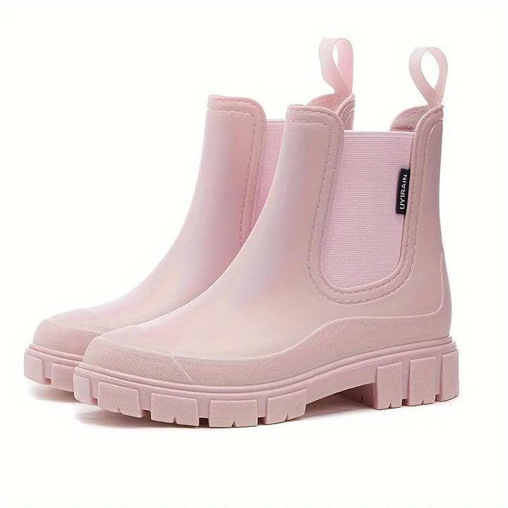 Light pink waterproof Chelsea rain boots with a chunky lugged sole, side gussets, and pull tabs on a white background.