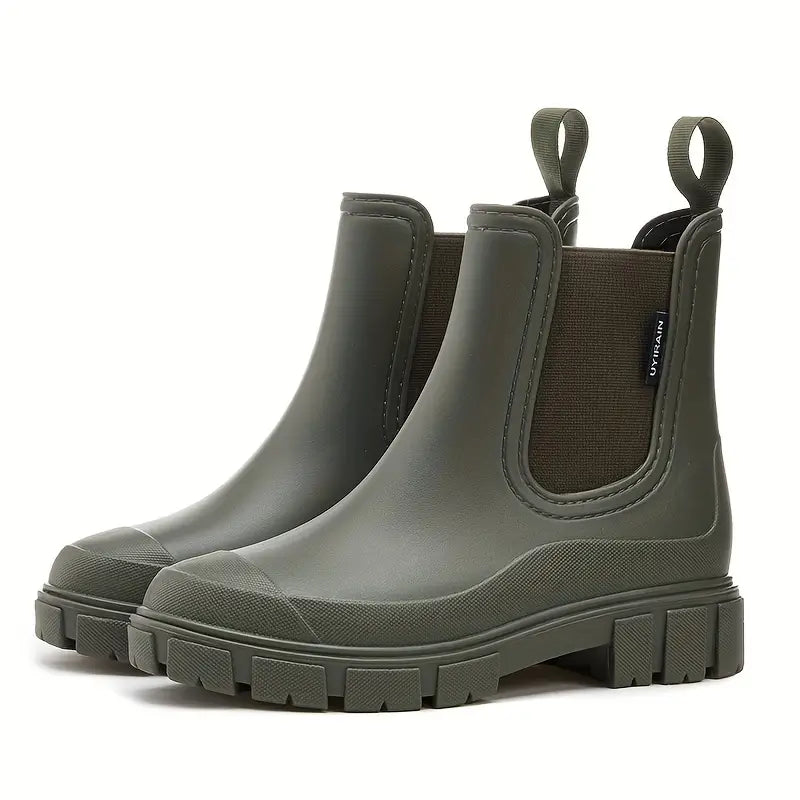 Olive green waterproof Chelsea rain boots with a chunky lugged sole, side elastic gussets, and pull tabs.