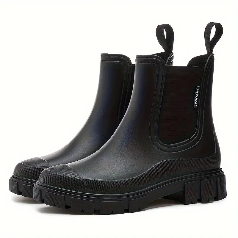 Black waterproof Chelsea rain boots with a chunky lugged sole, side gussets, and pull tabs on a white background.