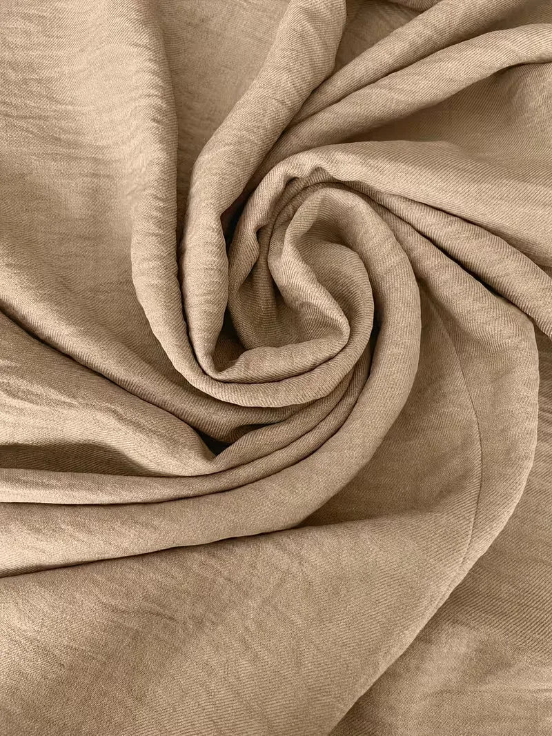 Close-up of the Etta dress's textured, light beige fabric, showcasing its relaxed drape and quality.