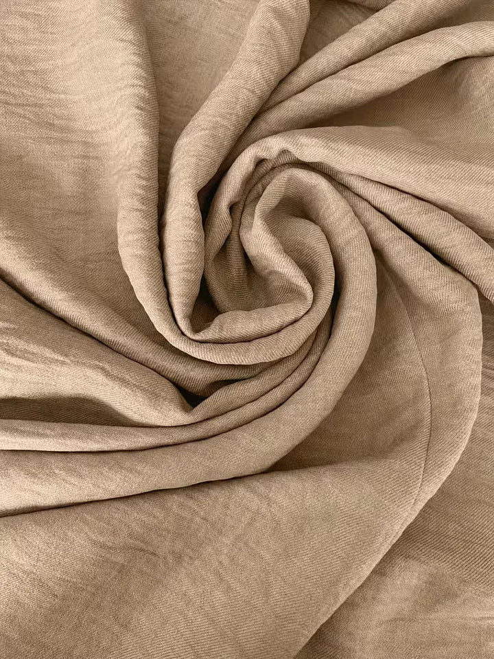 Close-up of the Etta dress's textured, light beige fabric, showcasing its relaxed drape and quality.