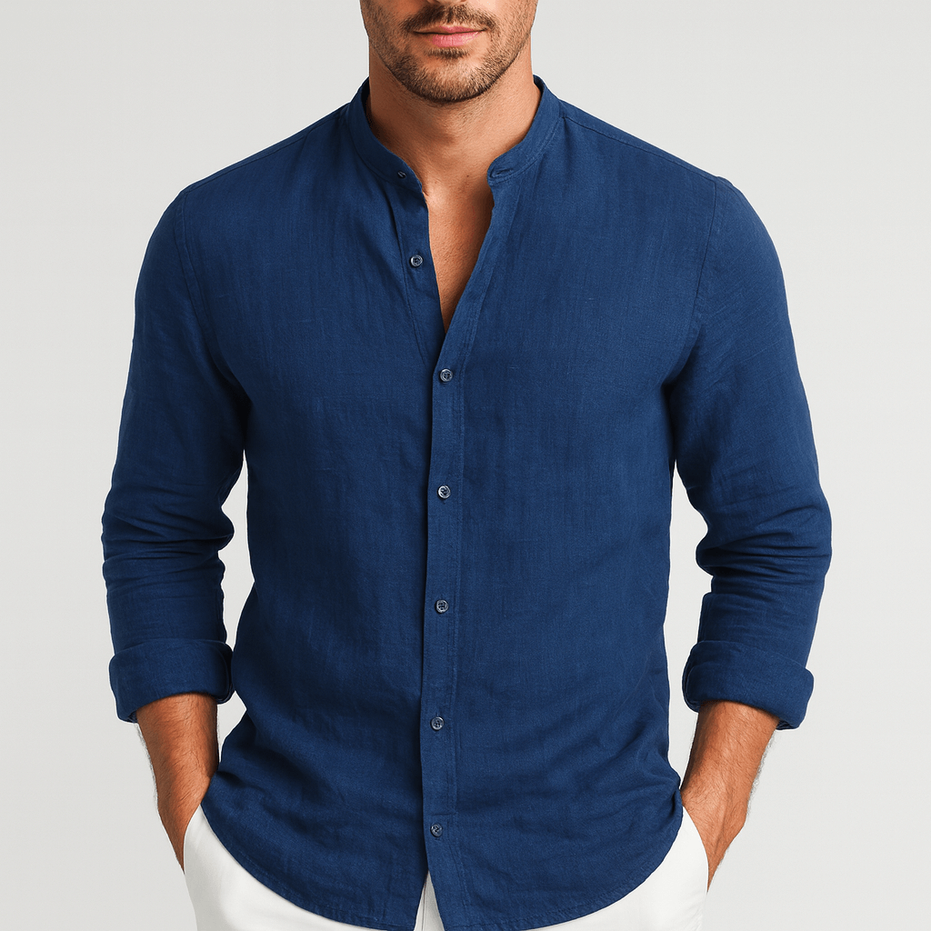 Navy blue long-sleeve linen shirt with a grandad collar and relaxed fit, worn with white trousers.