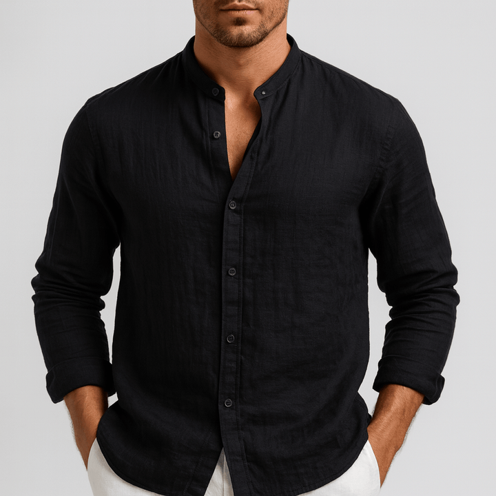 Man wearing a black long-sleeve linen shirt with a grandad collar and relaxed fit, styled with white trousers.