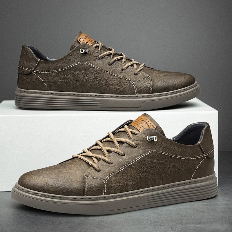 Brown leather low-top trainers with lace-up front, contrast stitching, and a durable rubber sole on a white display block.