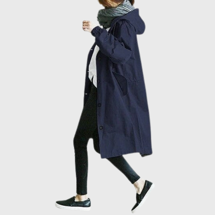 Navy blue oversized hooded raincoat with a button-front, longline silhouette, and side pockets worn over black leggings.