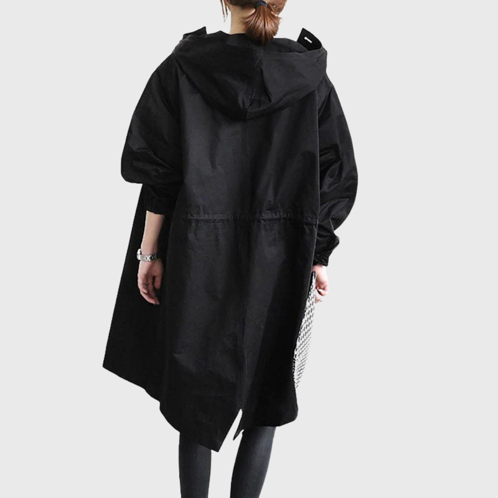 Back view of a black oversized waterproof raincoat with a hood and longline silhouette worn over leggings.