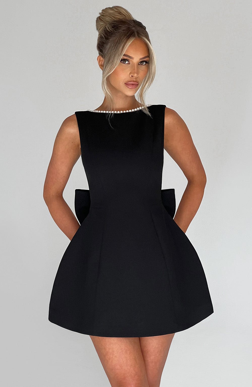 Sleeveless black mini dress with a pearl-trimmed neckline and a structured fit-and-flare silhouette.