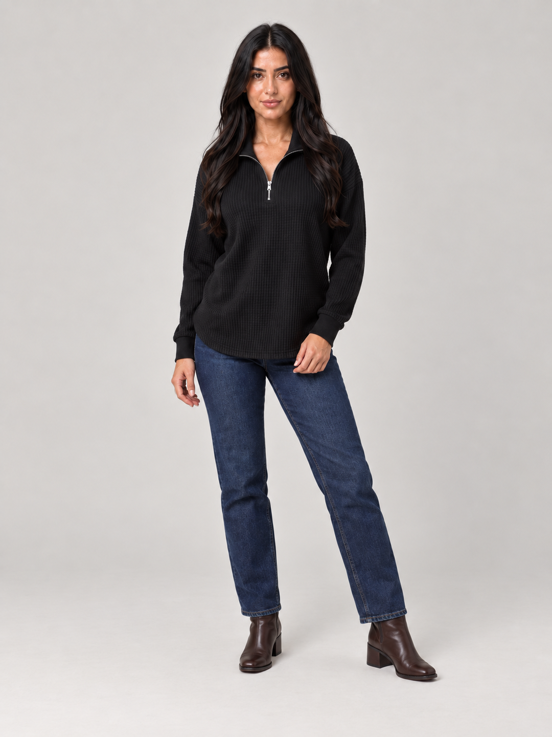 Black relaxed-fit waffle knit jumper featuring a stylish half-zip funnel neck, paired with classic blue jeans.