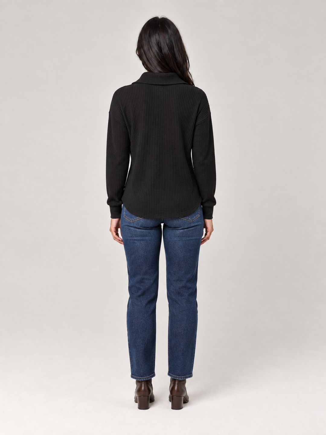Back view of a black relaxed-fit waffle knit half-zip jumper paired with blue jeans.